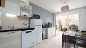 A modern kitchen with white appliances, a dishwasher, and a dining area with a table and chairs.