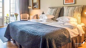 Een hotelkamer met een groot bed, een stoel, een bureau en een raam met gordijnen.
