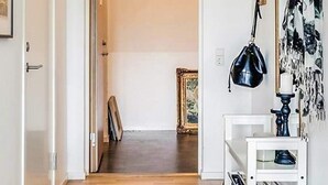 Een gang met houten vloer die leidt naar een kamer met een witte deur.