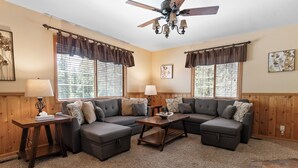 A living room with a sectional sofa, two side tables, a coffee table, and a ceiling fan. - Stony Creek Cabin (Big Bear Lake)