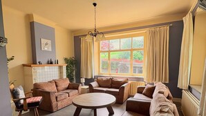 A living room with a sofa set, a round coffee table, and a fireplace. - Group Home in La Roche With Sauna (La Roche-en-Ardenne)