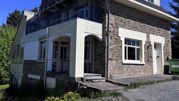 A two-story house with a stone facade, a balcony on the upper floor, and a front entrance with steps. - Group Home in La Roche With Sauna (La Roche-en-Ardenne)