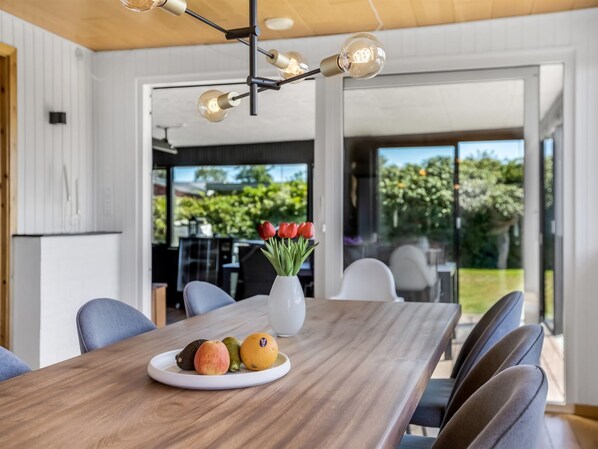 A modern dining area with a wooden table, chairs, and a fruit plate.