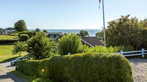 A coastal property with a flagpole, neatly trimmed hedges, and a view of the sea.