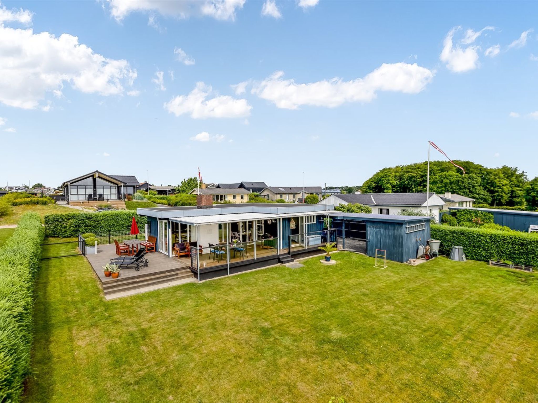 A modern house with a large patio area, a covered outdoor seating area, and a well-maintained lawn.