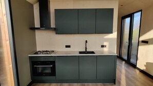 A modern kitchen with a built-in oven, a gas stove, and a black range hood. - Spacious Nature Retreat (Bant)
