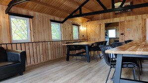 A wooden interior with a dining table and chairs, a sofa, and large windows. - Spacious Nature Retreat (Bant)