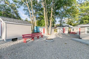 Un terrain de camping doté de cabanes aménagées de type caravane, d’un foyer et d’un banc rouge.