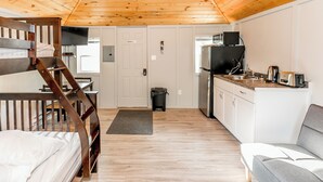 A compact room with a bunk bed, kitchenette, and seating area. - Wasaga Beach Summer Cottages & Cabins (Wasaga Beach)