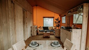 Een houten interieur met een eettafel voor vier personen, een bank en een keukenhoek.