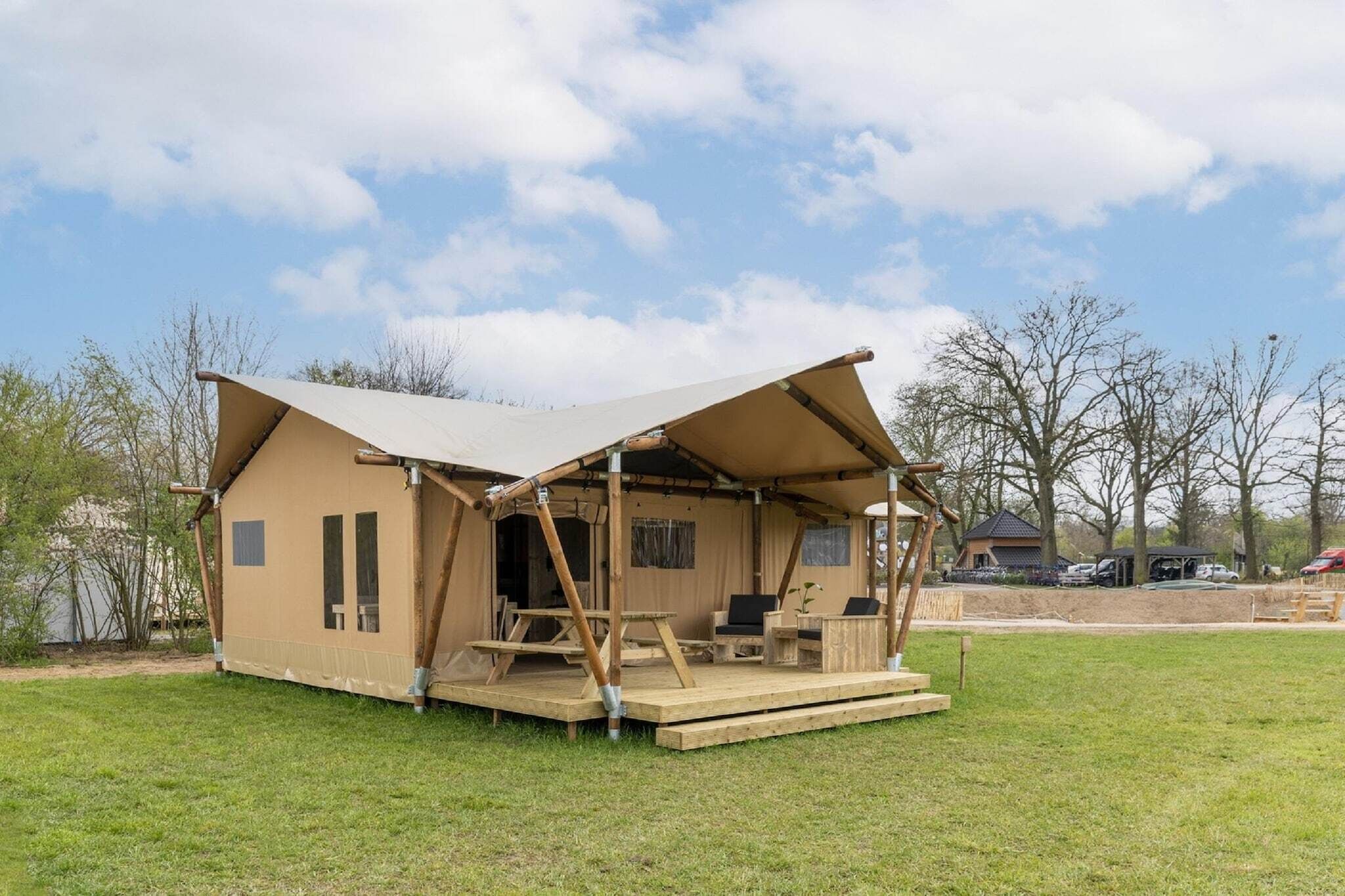 A single-story, A-frame wooden structure with a covered porch, a small deck, and a patio area with seating.