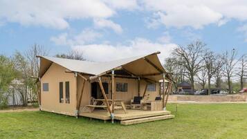A single-story, A-frame wooden structure with a covered porch, a small deck, and a patio area with seating.