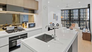 A modern kitchen with a central island, built-in appliances, and a large window overlooking a cityscape. - Stylish 1-Bedroom Near Casino Luxe Tower Street & South Bank (Brisbane City)
