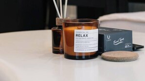 A candle labeled "RELAX" on a table with a box and a stone. - Stylish 1-Bedroom Near Casino Luxe Tower Street & South Bank (Brisbane City)