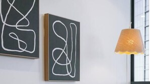 A modern living room with a sofa, two abstract paintings, and a lamp. - Stylish 1-Bedroom Near Casino Luxe Tower Street & South Bank (Brisbane City)