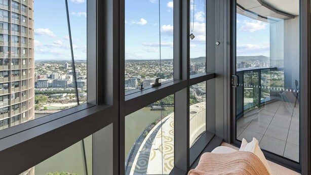 A high-rise apartment with large windows offering a city view, a balcony with a view of a river, and a modern interior design. - Stylish 1-Bedroom Near Casino Luxe Tower Street & South Bank (Brisbane City)