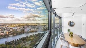 A modern room with a large window offering a city view, a round table with chairs, and a decorative vase.