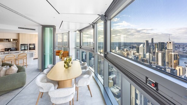 A modern interior with a dining area, kitchen, and large windows offering a city view.
