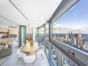 A modern interior with a dining area, kitchen, and large windows offering a city view.