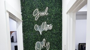 Un passadís amb una paret verda i un cartell de neó que diu 'Good vibes only'.