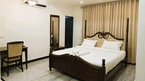 Une chambre d’hôtel avec un grand lit, un bureau, une chaise, un miroir et un luminaire au plafond.