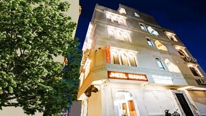 Un hôtel avec une enseigne indiquant « JHEEL MAHAL » et un arbre au premier plan.