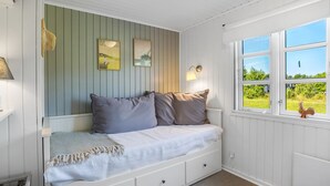 Une chambre confortable avec un lit intégré, une fenêtre donnant sur un paysage verdoyant et deux lampes fixées au mur.
