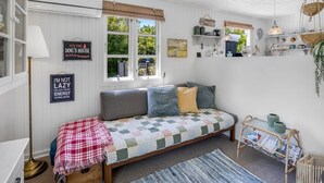 Une pièce confortable avec un lit, une lampe sur pied, une fenêtre donnant sur un beau paysage et une étagère remplie de divers objets.