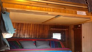 Interno di una baita in legno con un letto, pareti in legno e una porta.