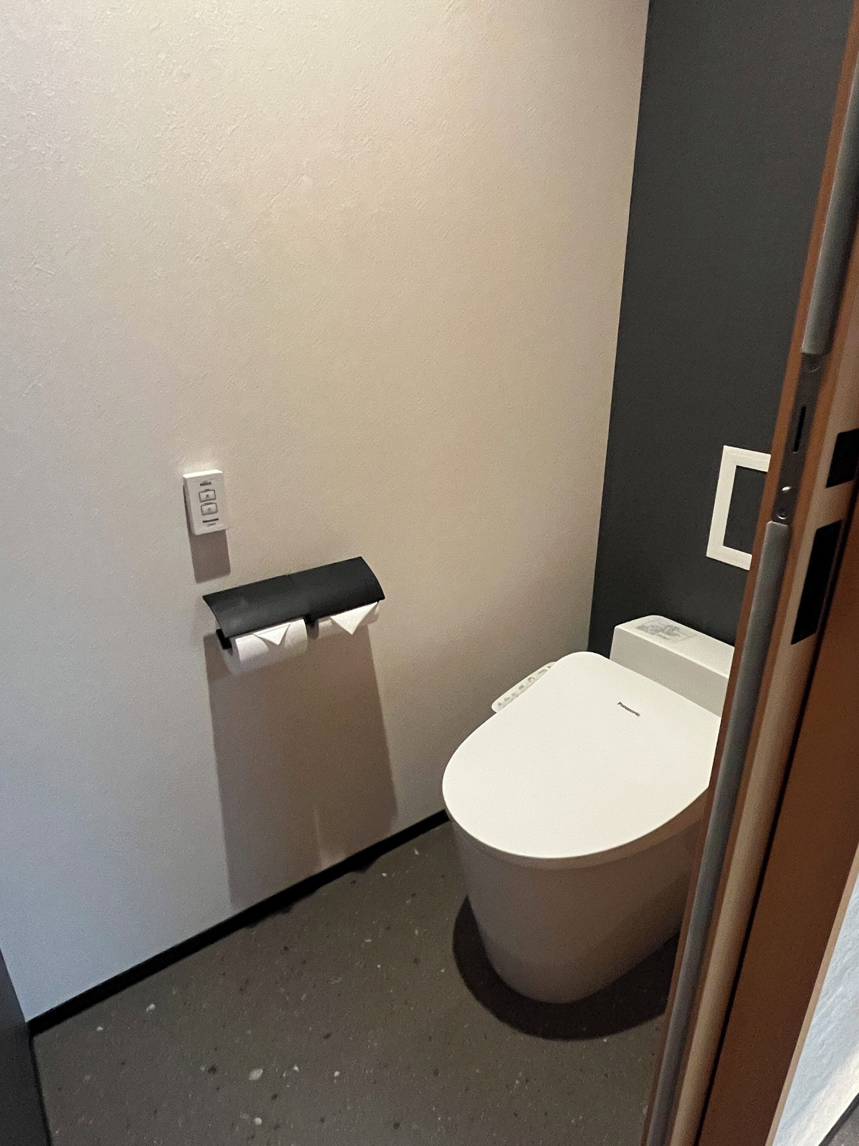 Un baño pequeño y funcional con inodoro, toallero y un interruptor de luz en la pared.