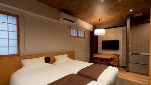 Una habitación de hotel con una cama grande, una mesa de comedor, un televisor y un armario.