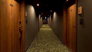 Un pasillo de hotel con puertas de madera numeradas 203 y 204, piso alfombrado e iluminación empotrada.