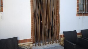 A doorway with a decorative curtain, a window with metal bars, and wicker furniture.