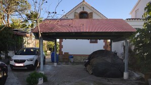 A covered car parking area with a white car parked under a red roof.