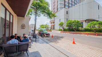 A building with a modern design, a paved sidewalk, and a street with parked motorcycles and traffic cones.
