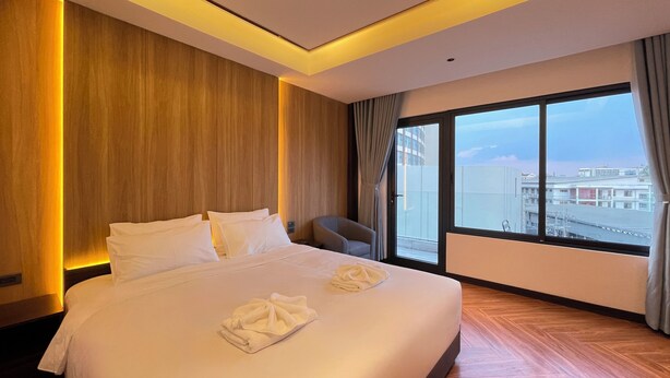 Ein Hotelzimmer mit einem großen Bett, einem Sessel und einem großen Fenster mit Blick auf die Stadt.