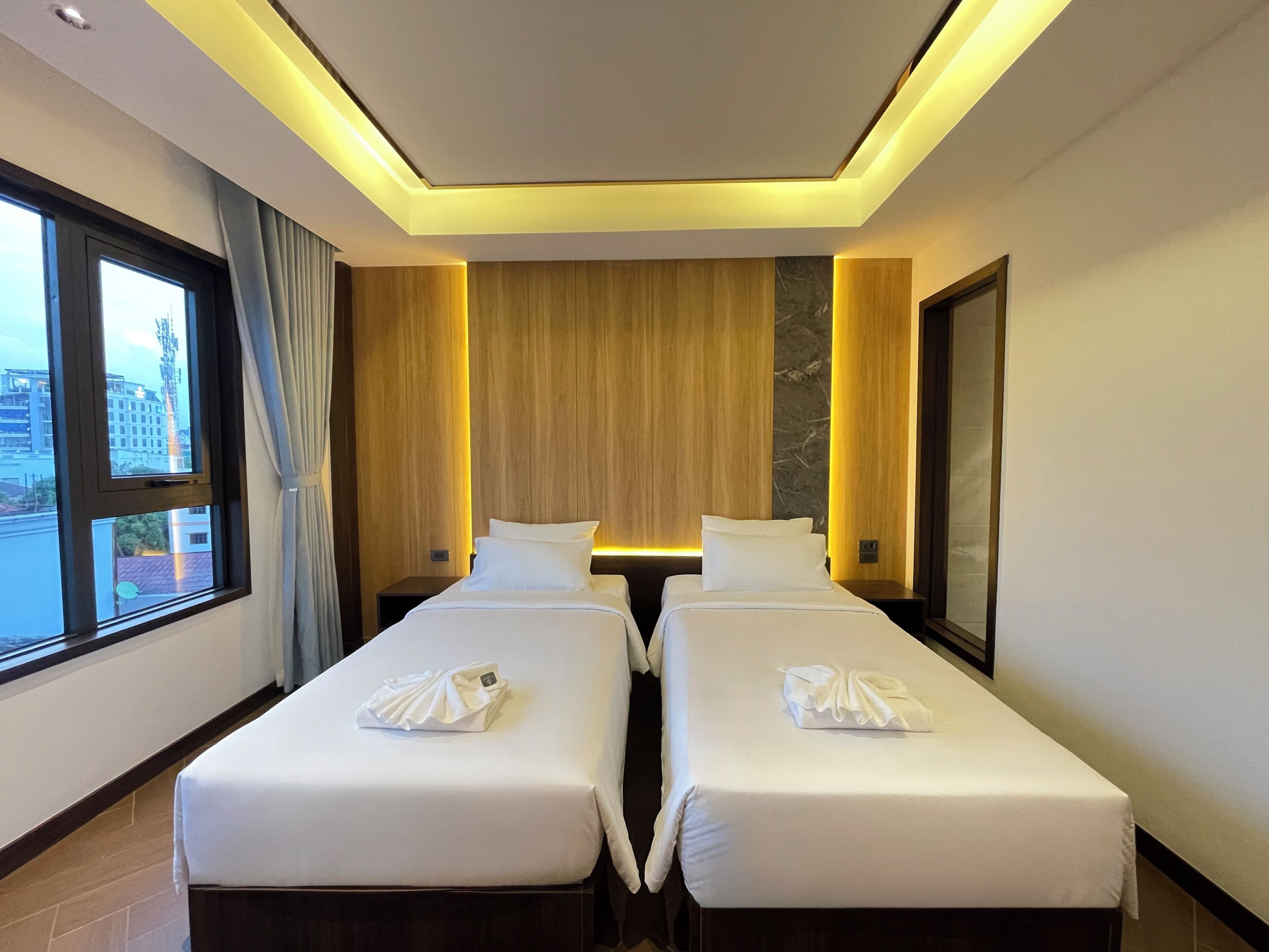 A hotel room with two beds, a large window, and a view of the city.