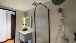 Ein modernes Badezimmer mit einer gläsernen Duschkabine, einem Waschtisch mit Spiegel und einer Toilette.
