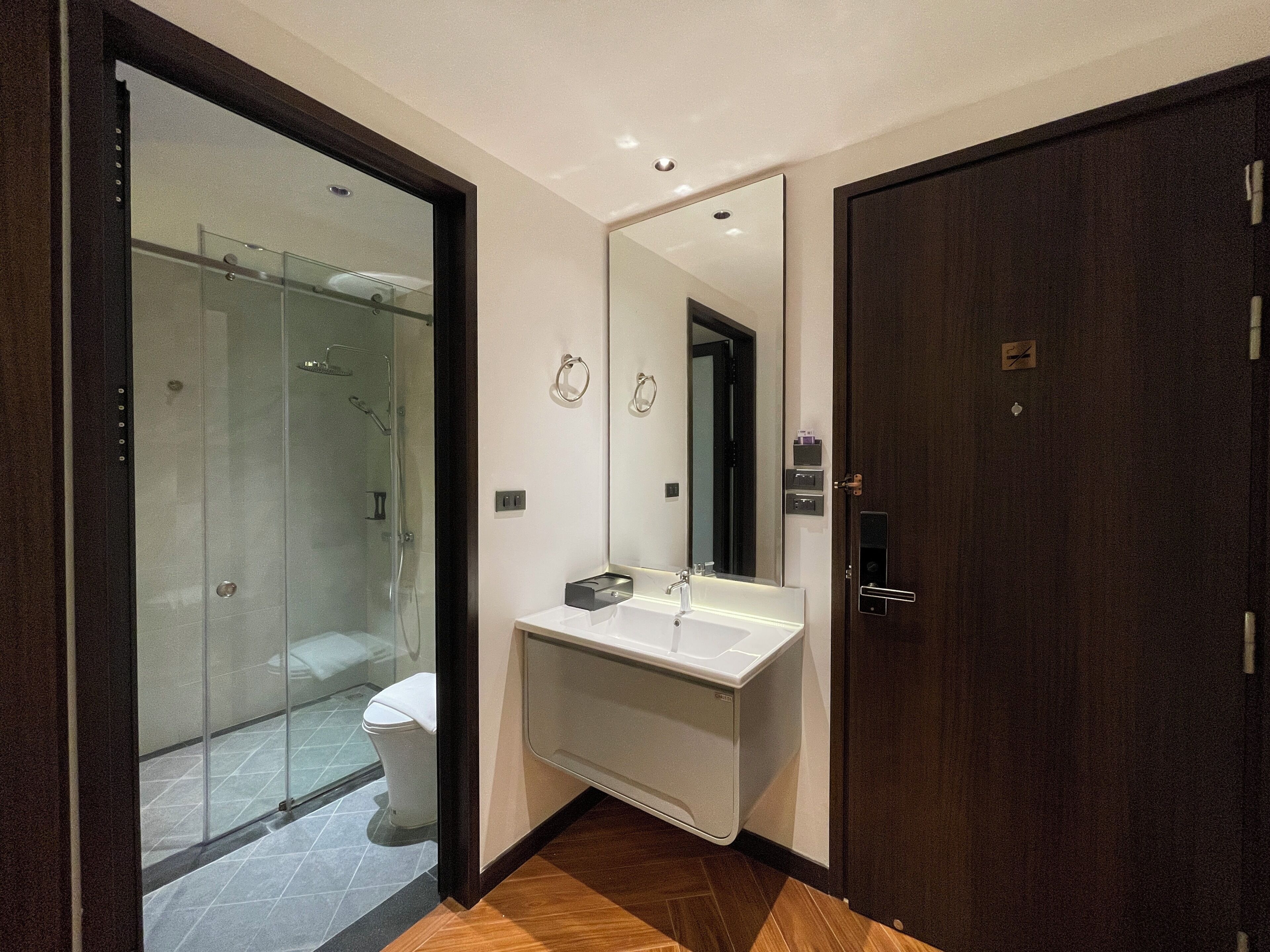 Un baño moderno con cabina de ducha de vidrio, un lavabo blanco y un espejo grande.