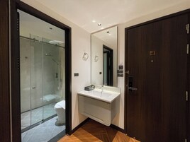 Un baño moderno con cabina de ducha de vidrio, un lavabo blanco y un espejo grande.