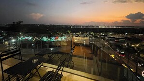 Eine Dachterrasse mit Glasgeländern, einem Tisch und Stühlen.