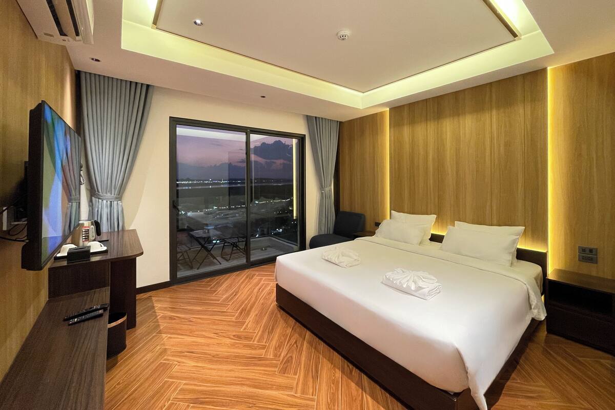 Une chambre d’hôtel avec un grand lit, une télévision, un bureau et une vue sur le paysage urbain par la fenêtre.