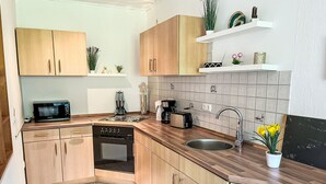 Una cocina moderna con armarios de madera, microondas, estufa, lavamanos y varios electrodomésticos.