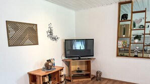 Una sala de estar con un mueble de madera para entretenimiento, un televisor y una estantería.