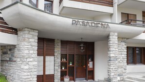 A building entrance with a stone facade, wooden doors, and a sign reading "PASADENA".