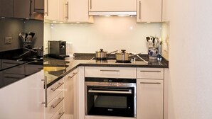 A modern kitchen with white cabinets, a built-in oven, and a coffee maker.