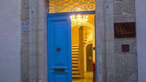 Una puerta azul con una reja de hierro forjado, un muro de piedra y una lámpara arriba.