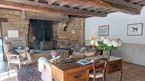 Ein rustikales Interieur mit Kamin aus Stein, Holzmöbeln und Fliesenboden.