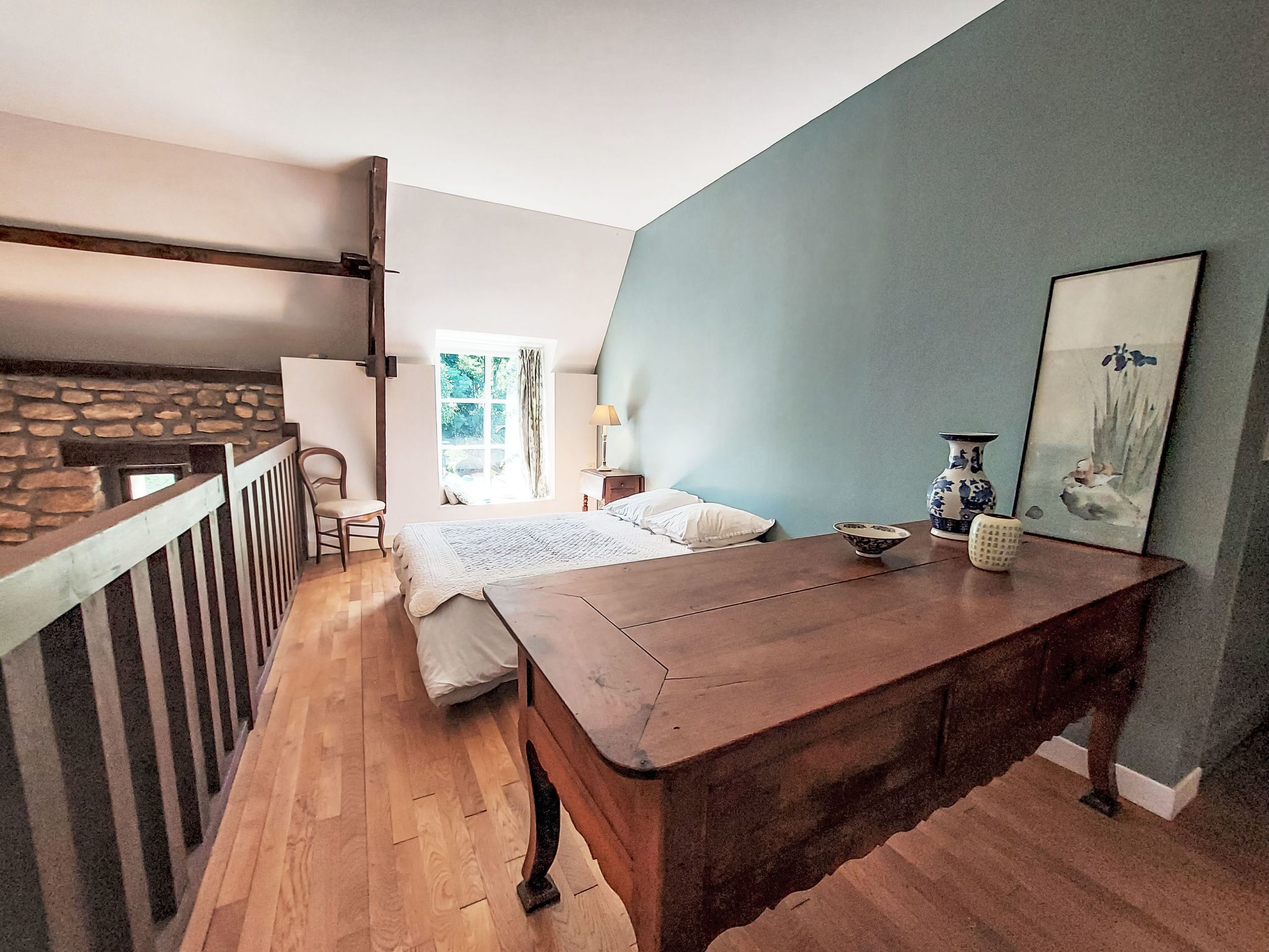 A bedroom with a wooden bed, a nightstand, a lamp, and a painting on the wall.