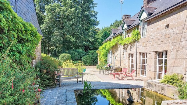 Ein Innenhof mit Teich, Steinweg, Bänken und Sitzgelegenheiten im Freien.